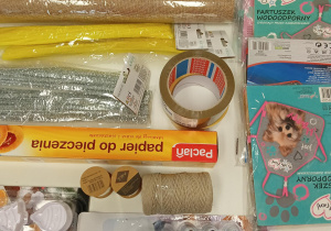 Na zdjęciu papier do pieczenia, foremki do ciastek, wodoodporne fartuszki, sznurki, żółte i srebrne filofany, taśma, farby akrylowe i srebrne koraliki
