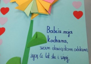 Laurka na Dzień Babci z przyklejonym kwiatkiem origami i napisem: Babciu moja kochana, swoim obowiązkom oddana, życzę Ci lat stu i więcej, dziękuję Ci za Twoje serce.