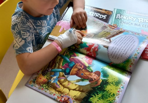 Chłopiec czytający kolorową książkę.