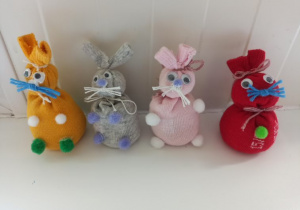 Cztery króliki wykonane ze skarpetek w kolorach: żółtym, szarym, różowym i czerwonym.