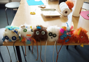 Maskotki wykonane przez dzieci, ze sztucznego futra, posadzone na stole.
