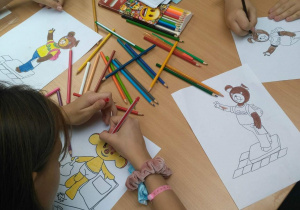 Dzieci kolorują obrazki z bohaterami bajek.