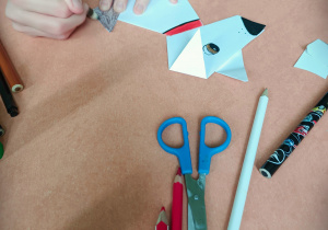 Dziewczynka wykonuje pieska techniką origami i koloruje go.