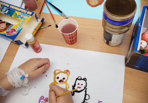 Dzieci malują misie farbami. Na pierwszym planie rysunek z trzema misiami.