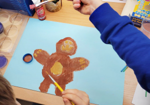 Dziecko maluje brązowego misia z miodowym brzuszkiem.