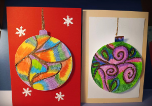 Dwie kartki świąteczne z narysowanymi kolorowymi bombkami, posypanymi brokatem.