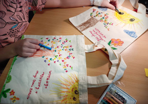 Dziecko rysuje wzorki na lnianej torbie, w prezencie dla babci i dziadka.