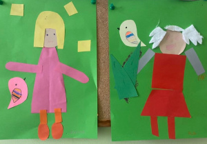 Na korkowej tablicy wiszą dwie prace plastyczne. Na zielonym tle na jednej pracy widzimy kobietę z żółtymi włosami w różowej sukience. Na drugiej kobietę w czerwonej sukience z białymi włosami, z ptaszkiem na trzymanej przez nią choince.