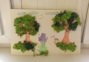 Praca plastyczna wykonana na białej kartce. Po lewej i prawej stronie namalowane brązowe drzewa z zielona korona wyklejona mchem chrobotkiem. Pomiędzy drzewami namalowane są fioletowe kwiaty i biało-czarny bocian.