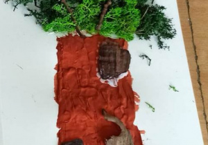Praca plastyczna przedstawiająca drzewo, pień drzewa jest brązowy wyklejony z plasteliny i drewienek, korona drzewa z mchu chrobotka.