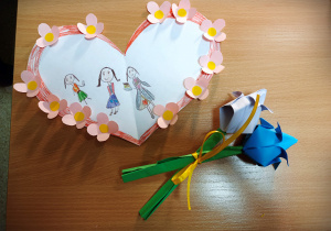 Prace wykonane dla Mam z okazji ich święta. Jedna, to laurka w kształcie serca, oklejna wokół różowymi kwiatkami. Druga to bukiecik z dwóch tulipanów, niebieskiego i fiołkowego, obwiązanych żółtą wstążeczką. Tulipany są z papieru, wykonane techniką origami.