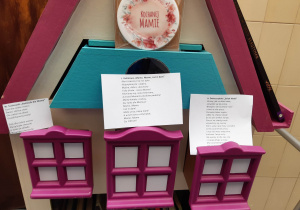 Na zdjęciu różowo niebieski Bajkowóz z książkami. Na szufladkach umieszczone wiersze związane z Dniem Matki, nad wierszami umieszczona tabliczka z napisem Kochanej Mamie.