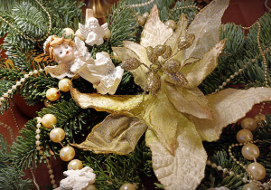 Stroik świąteczny z aniołkiem, gałązkami jodły, kwiatem w kolorze kremowym ze złotym brokatem i łańcuchem z perłowych koralików.