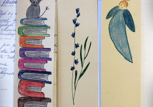 Trzy zakładki zrobione przez dzieci. Na jednej widać króliczka, który siedzi na stosie książek, na drugiej gałązkę obsypaną kwiatkami, na trzeciej aniołka.