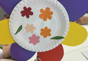 Kwiat zrobiony z białego talerzyka. Ozdobiono go i doklejono kolorowe płatki.