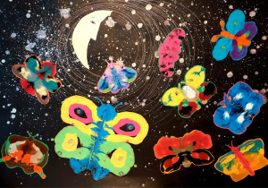 Obraz przedstawia fantazyjną, kosmiczną scenę z motywem motyli na tle nocnego nieba: Opis szczegółowy: Tło: Dominujący kolor to głęboka czerń, przypominająca przestrzeń kosmiczną. Na tle widoczne są białe plamy i kropki, które wyglądają jak gwiazdy lub rozpryski farby, nadając efekt galaktyki. W centralnej części znajduje się duży biały kształt przypominający księżyc w fazie pierwszej kwadry, otoczony koncentrycznymi, cienkimi liniami tworzącymi efekt orbit. Motyle: Na obrazie rozmieszczonych jest dziewięć kolorowych motyli, każdy w innym zestawieniu barw: Największy motyl w dolnej części ma niebieskie skrzydła z żółtymi i różowymi akcentami. Pozostałe motyle są w odcieniach czerwieni, pomarańczu, zieleni, różu, błękitu i żółci, z kontrastowymi plamami i wzorami. Motyle są namalowane w stylu abstrakcyjnym – ich kształty są uproszczone, a kolory intensywne, często nakładające się na siebie. Charakter kompozycji: Połączenie motyli z kosmicznym tłem tworzy surrealistyczny efekt – jakby motyle unosiły się w przestrzeni kosmicznej. Kolorystyka jest bardzo żywa i kontrastowa: neonowe barwy motyli wyróżniają się na ciemnym tle.