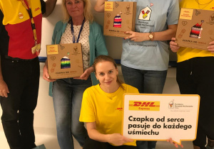Wolontariusze i nasza nauczycielka ewaU.prezentują paczki z ręcznie robionymi czapkami w ramach akcji „Czapka od serca” Fundacji Ronalda McDonalda i DHL.