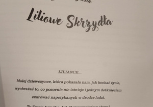 Na zdjęciu widać stronę z dedykacją otwartej książki. Strona jest utrzymana w prostym, eleganckim stylu — czarny tekst na białym tle, bez ilustracji. U góry znajdują się dwa wiersze: imię i nazwisko autorki: Lilianka Błasik, tytuł książki: „Liliowe Skrzydła”. Niżej, wyśrodkowany, znajduje się nagłówek „LILIANCE…”, zapisany wielkimi literami, co podkreśla, że dedykacja jest skierowana do konkretnej osoby — Lilianki. Pod nagłówkiem widnieje ciepły, emocjonalny tekst o małej dziewczynce, która potrafiła kochać życie, wyobrażać sobie rzeczy pozornie nieistniejące i „czarować” ludzi spotykanych na swojej drodze. Dalej pojawia się zdanie: „To Twoja książka, Lil. Dotrzymałyśmy słowa!” — brzmi jak spełnienie obietnicy złożonej dziecku. Na końcu dedykacja kończy się słowami miłości i podpisem dwóch osób: „Twoje autorki wspomagające – Marta i Agnieszka.”