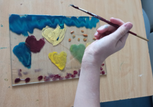 Ręka dziecka malującego obrazek z sercami