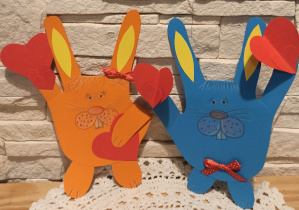 Dwa walentynkowe króliczki wycięte z kolorowego papieru z sercami w łapkach