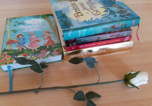 biała róża i książki leżące na stole
