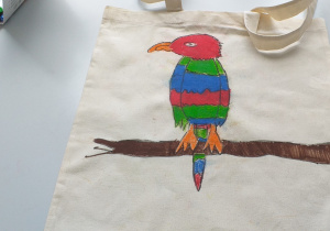 kolorowa papuga siedząca na gałęzi namalowana pastelami na torbie na zakupy...