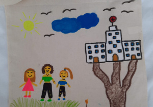 na torbie narysowne drzewo z budynkiem zamiast liści, oraz trójka dzieci w kolorowych ubrankach. Nad nimi piekne słońce, mała chmurka i lecące ptaki...