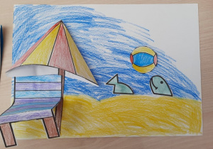 Rysunek dziecka "Plażing" - morze, plaża. Doklejony leżak i parasol plażowy stwarzają trójwymiar pracy. W wodzie piłka i ryby.