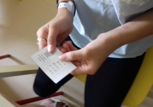 Zdjęcie pokazuje dłonie uczennicy z kartą zadań egzaminacyjnych.