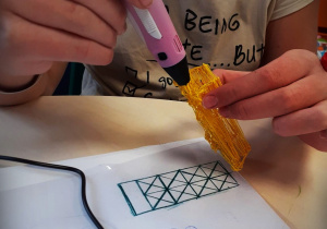 Dziecko tworzące żółtą figurę geometryczną, długopisem 3 D.
